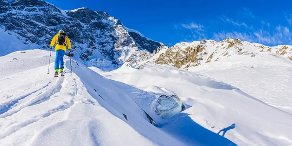 Ski de montagne marchant le long d'une crête enneigée avec des skis — Photo