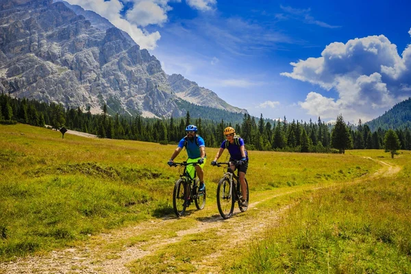 Mountain biking couple with bikes on track, Cortina d'Ampezzo, D