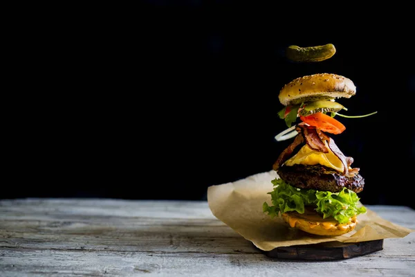 Hamburger s realistickou létající ingredience. Chutné uzené mříž — Stock fotografie