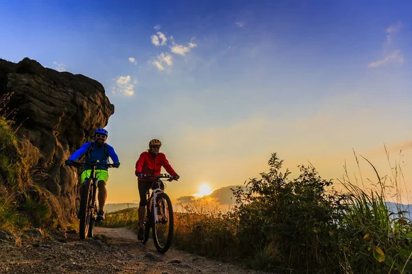 Jazda na rowerze, Kobieta i mężczyzna, jazda na rowerach w zachód Słońca Góry Las — Zdjęcie stockowe