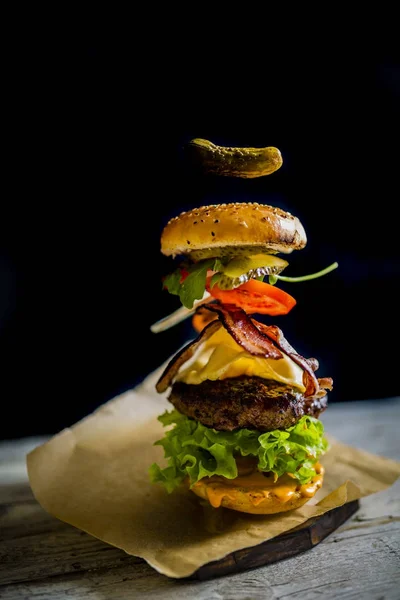 Hamburguesa con ingredientes voladores realistas. Sabrosa parrilla ahumada —  Fotos de Stock