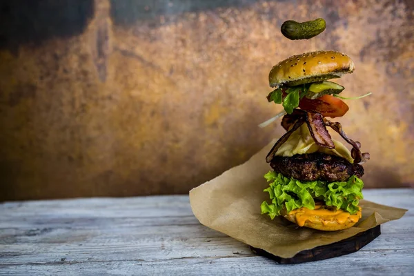 Hamburguesa con ingredientes voladores realistas. Sabrosa parrilla ahumada — Foto de Stock