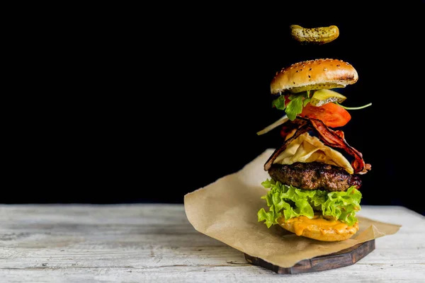 Hamburger s realistickou létající ingredience. Chutné uzené mříž — Stock fotografie