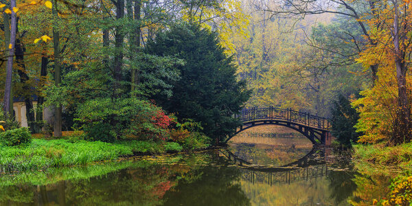 Scenic view of misty autumn landscape with beautiful old bridge 