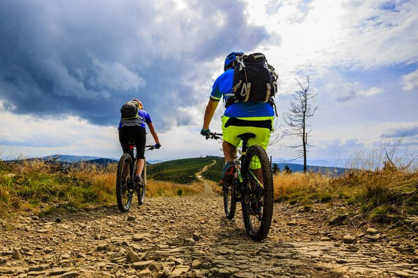 Cycling, mountain biker couple on cycle trail in autumn forest. 