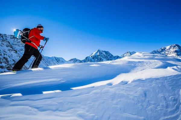 Alpinista sci di fondo camminando lungo un crinale innevato con — Foto Stock