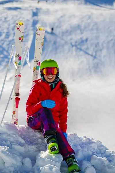 Ritratto di giovane ragazza felice seduta sulla neve con sci in vittoria — Foto Stock
