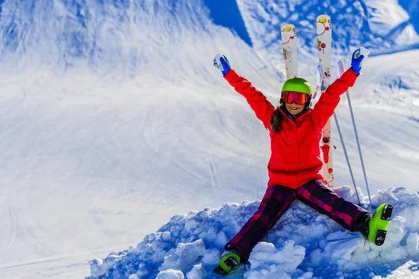 Портрет счастливой молодой девушки, сидящей в снегу с лыжами в победе — стоковое фото