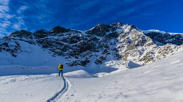 Alpinista sci di fondo camminando lungo un crinale innevato con — Foto Stock