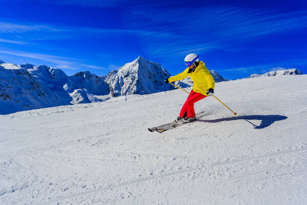 Женщина катается на снегу в солнечный день в горах. Лыжи в выигрыше
