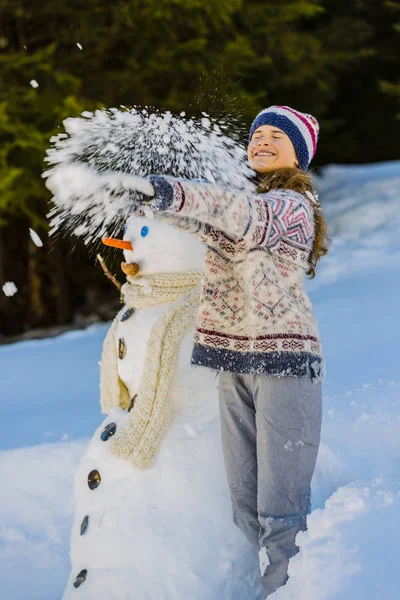 Feliz adolescente sonriente jugando con un muñeco de nieve en una victoria nevada —  Fotos de Stock