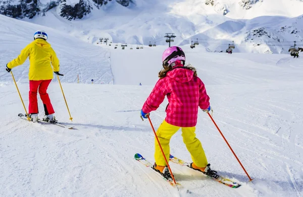 Женщина катается на лыжах с дочерью на снегу в солнечный день в горах — стоковое фото