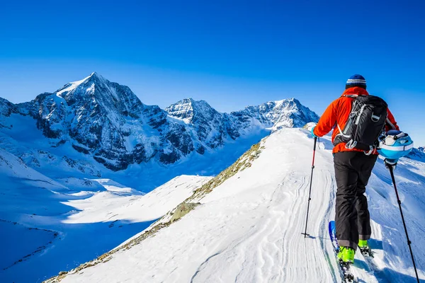 Mountaineer backcountry ski promenad längs en snöig bergskam med skidor i — Stockfoto