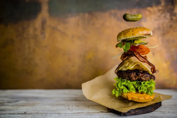 Hamburger s realistickou létající ingredience. Chutné uzené mříž — Stock fotografie