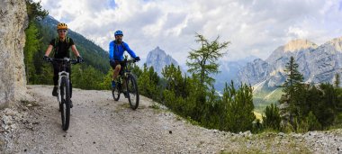 Tourist cycling in Cortina d'Ampezzo, stunning rocky mountains o clipart
