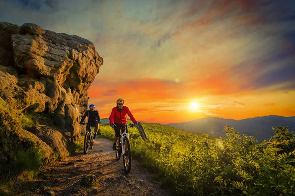 Mountain cykling kvinnor och man rider på cyklar vid solnedgången mountain — Stockfoto