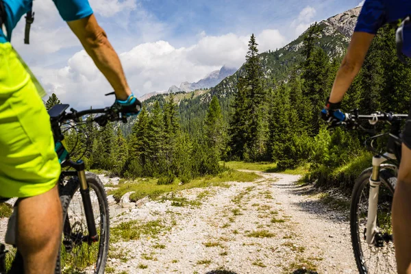 Cycling couple with bikes on track, Cortina d\'Ampezzo, Dolomites