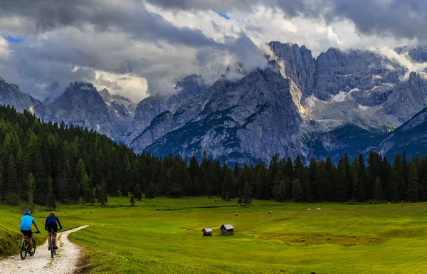 Couple cycling in Cortina d'Ampezzo, stunning Dolomites mountain — Stock Photo, Image