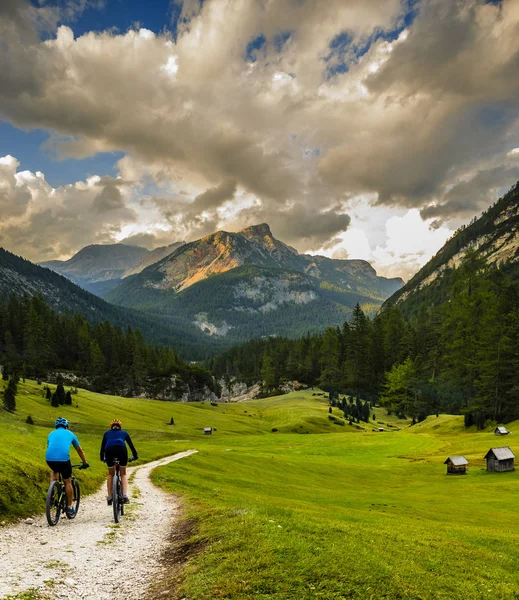 Cycling woman and man riding on bikes in Dolomites mountains and — Stock Photo, Image