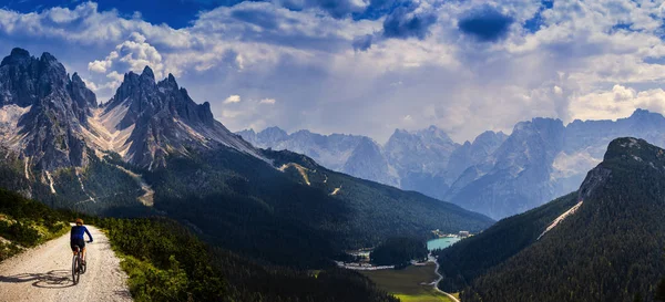 Tourist cycling in Cortina d'Ampezzo, stunning rocky mountains o — Stock Photo, Image