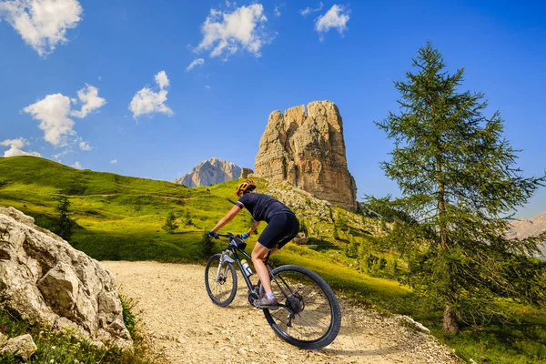 Woman cycling in Cortina d'Ampezzo, stunning Cinque Torri and To — Stock Photo, Image