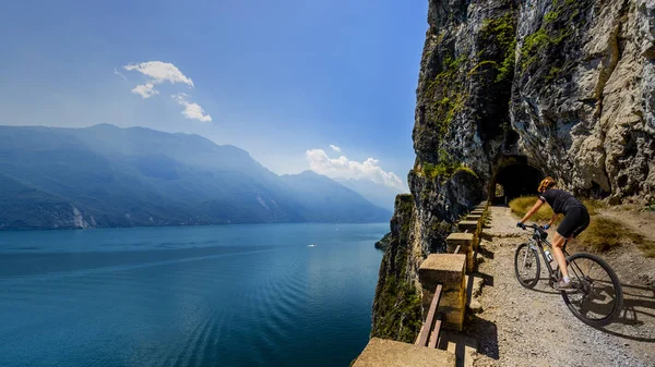 Ciclismo mulher andando de bicicleta ao nascer do sol montanhas e Garda lago l — Fotografia de Stock