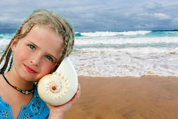 listening to the sea, beautiful young girl with shell on the beach