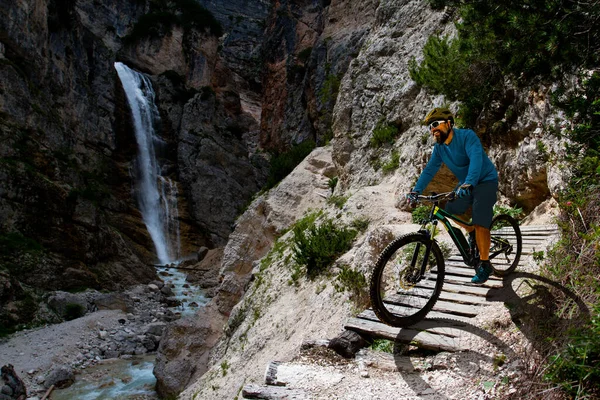 Man cycling on electric bike, rides mountain trail. Man riding on bike in Dolomites mountains landscape. Cycling e-mtb enduro trail track. Outdoor sport activity.