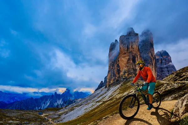 Cycling outdoor adventure in Dolomites. Cycling woman and man  on electric mountain bikes in Dolomites landscape. Couple cycling MTB enduro trail track. Outdoor sport activity.