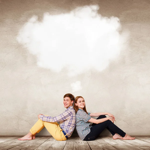 Casal feliz sentado no chão com nuvem branca acima da cabeça . — Fotografia de Stock