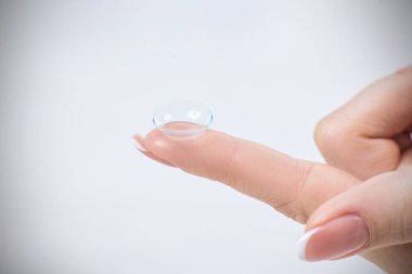 Mavi arkaplan üzerinde bir parmak üzerindeki lensler.