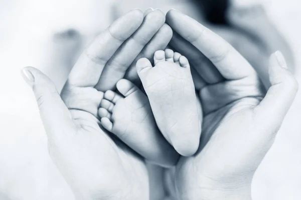 Gros plan petits pieds de bébé dans les mains . — Photo