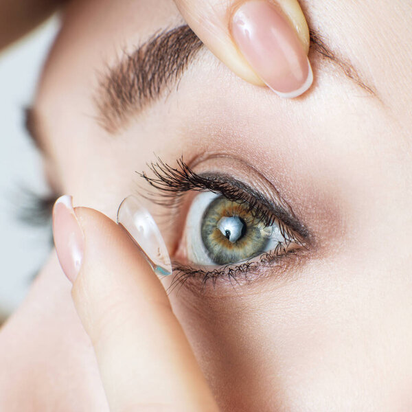 Close-up shot of young woman wearing contact lens.