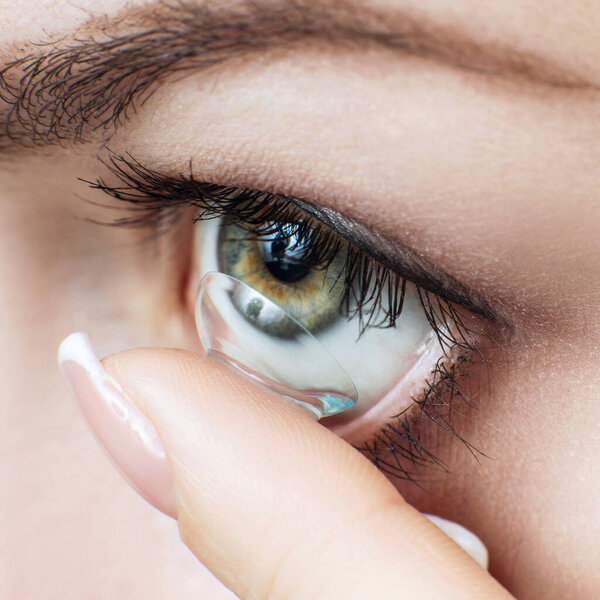 Close-up shot of young woman wearing contact lens.