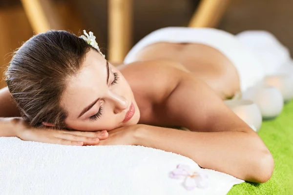 Mooie jonge vrouw liggend op een massagetafel. — Stockfoto