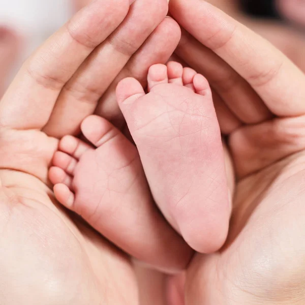 Primer plano pequeños pies de bebé en las manos . —  Fotos de Stock