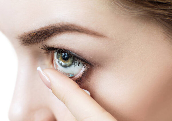 Close-up shot of young woman wearing contact lens.