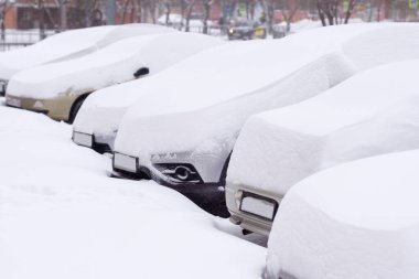 Cars completely covered with snow on parking. clipart