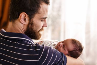 Mutlu baba yeni doğmuş bebeğini kucağında tutuyor..