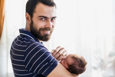 Mutlu baba yeni doğmuş bebeğini kucağında tutuyor..