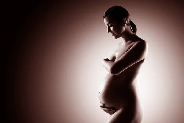 Nackte schwangere Frau mit einem riesigen schönen Bauch. — Stockfoto