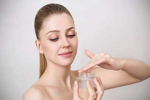 Hermosa mujer sosteniendo y presentando producto crema . — Foto de Stock