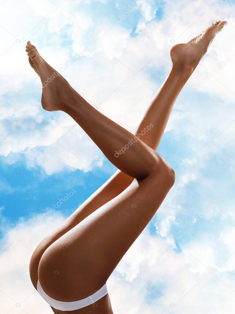 perfect female legs over cloudy sky background.