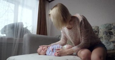 Anne kanepede oturup bebeğini okşuyor..