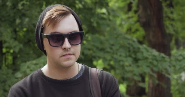 Young man hipster in sunglasses in the green park. — Stockvideo