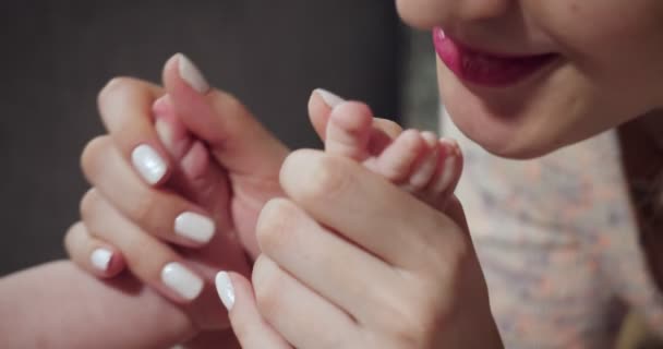 Μητέρα κρατά τα πόδια του μωρού στα χέρια και φιλιά. — Αρχείο Βίντεο