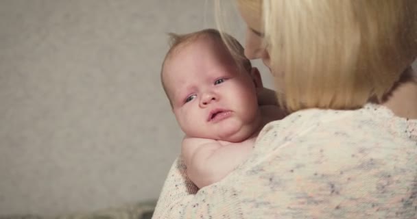 Joven madre sostiene y calma a su pequeña niña . — Vídeos de Stock