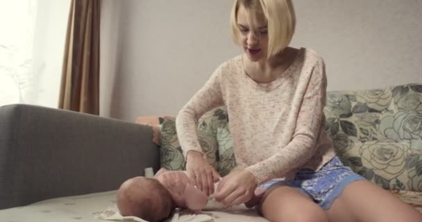 Молодая мама одевает подгузник на малышку . — стоковое видео