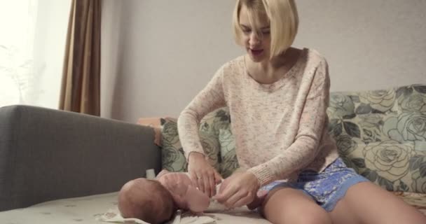 Young mother dresses a diaper on baby little girl. — Stock Video