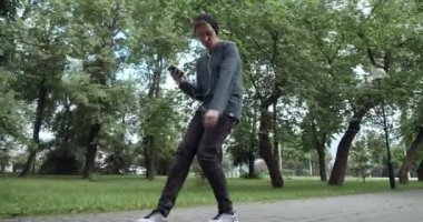 Arkadaki adam açık havada teypten müzik dinliyor.